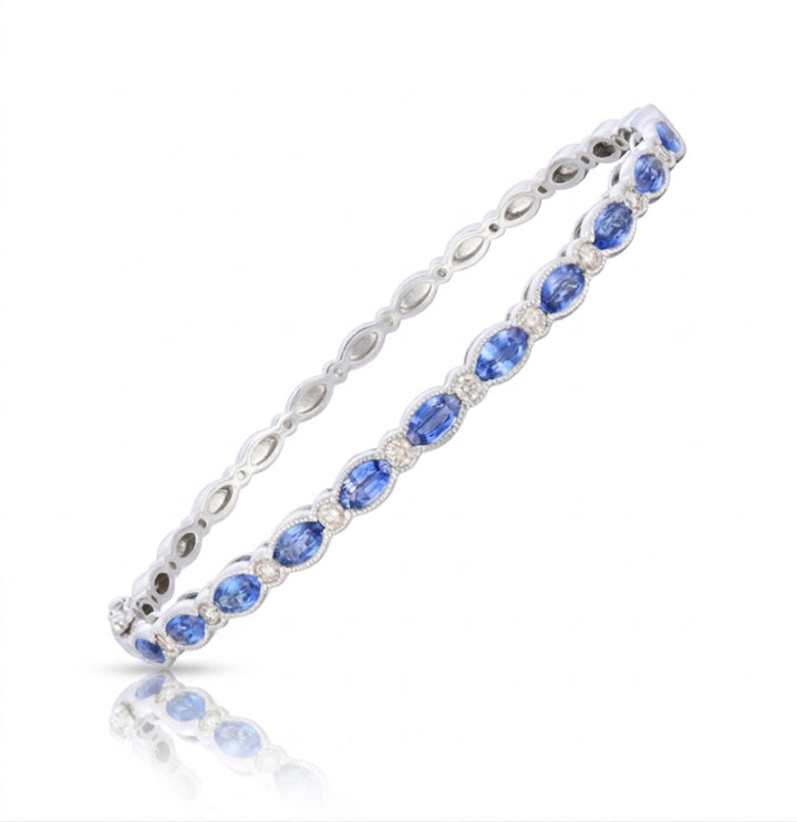 2.97 TOTAL CARAT WEIGHT OVAL SHAPED BLUE SAPPHIRE AND .40 TOTAL CARAT ROUND DIAMOND BEZEL BANGLE IN 14K WHITE GOLD